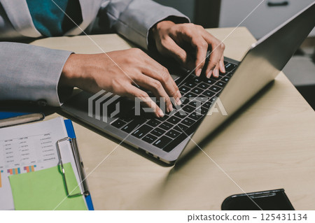 Working from home, Closeup business woman using laptop computer and analyzing financial report. Working from home, Closeup business woman using laptop computer and analyzing financial report. 125431134