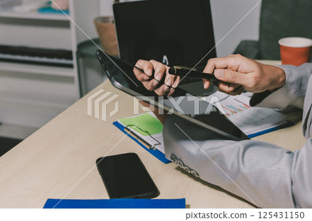 Working from home, Closeup business woman using laptop computer and analyzing financial report. 125431150