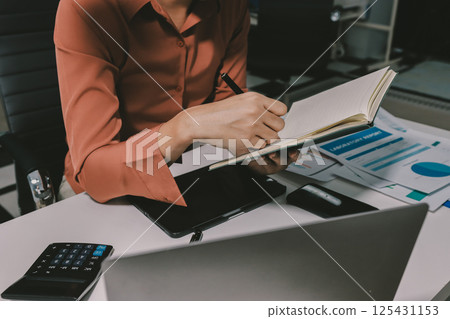 Working from home, Closeup business woman using laptop computer and analyzing financial report. Working from home, Closeup business woman using laptop computer and analyzing financial report. 125431153