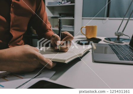 Working from home, Closeup business woman using laptop computer and analyzing financial report. 125431161