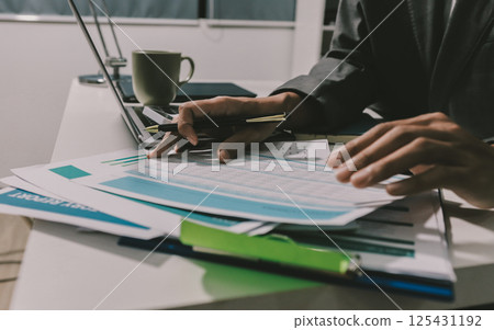 Working from home, Closeup business woman using laptop computer and analyzing financial report. 125431192