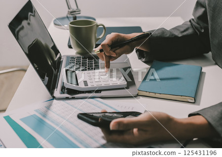 Working from home, Closeup business woman using laptop computer and analyzing financial report. 125431196
