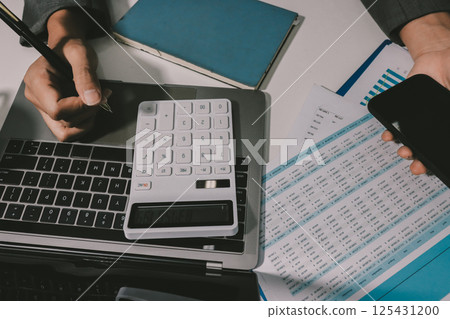 Working from home, Closeup business woman using laptop computer and analyzing financial report. Working from home, Closeup business woman using laptop computer and analyzing financial report. 125431200
