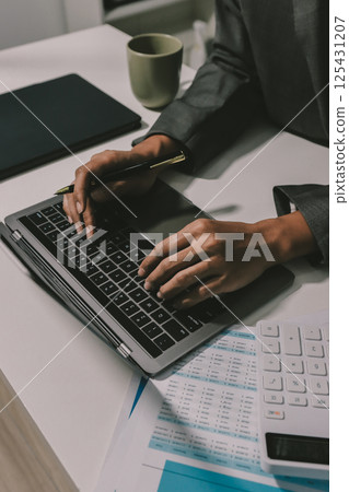 Working from home, Closeup business woman using laptop computer and analyzing financial report. 125431207