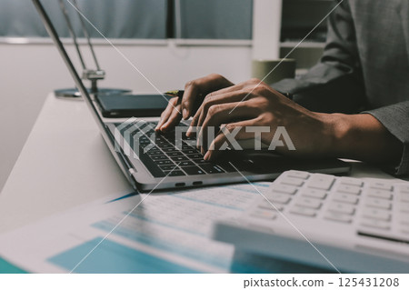 Working from home, Closeup business woman using laptop computer and analyzing financial report. 125431208