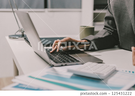 Working from home, Closeup business woman using laptop computer and analyzing financial report. Working from home, Closeup business woman using laptop computer and analyzing financial report. 125431222