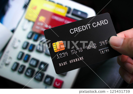 A hand holds a black credit card for payment process 125431739