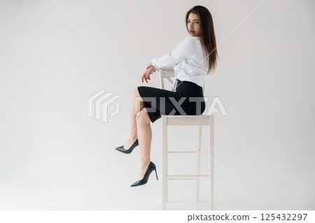 Young businesswoman sitting on chair in formal wear looking at camera 125432297
