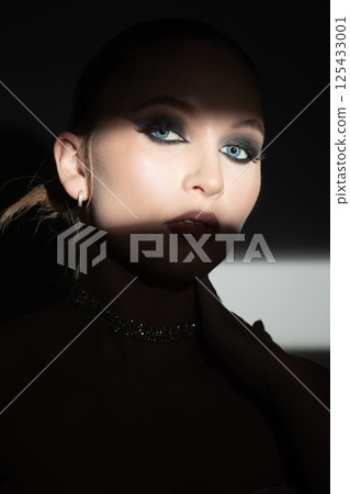 Woman portrait partly face covered with shadow 125433001