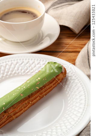 Delicious pastry with green icing served beside a cup of coffee on a wooden table during a cozy afternoon 125433821