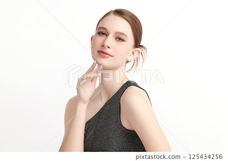 A beautiful young woman with clean, fresh skin against a white background. Skincare, facial treatment, cosmetology, beauty, and spa. An elegant portrait of an woman. 125434256