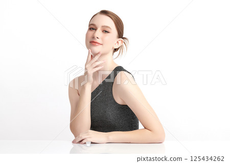 A beautiful young woman with clean, fresh skin against a white background. Skincare, facial treatment, cosmetology, beauty, and spa. An elegant portrait of an woman. 125434262