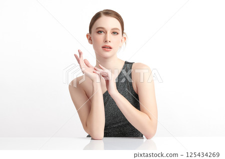 A beautiful young woman with clean, fresh skin against a white background. Skincare, facial treatment, cosmetology, beauty, and spa. An elegant portrait of an woman. 125434269