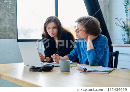 Teenage boy student with female mentor trainer teacher looking at laptop computer screen 125434659