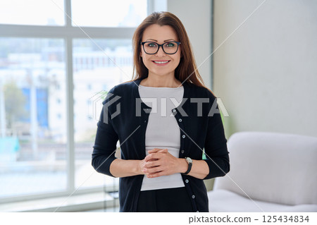 Portrait confident middle aged businesswoman posing with folded hands Portrait confident middle aged businesswoman posing with folded hands 125434834