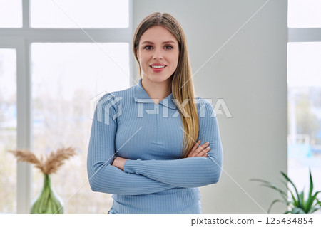 Portrait of confident young woman posing with crossed arms in home interior Portrait of confident young woman posing with crossed arms in home interior 125434854