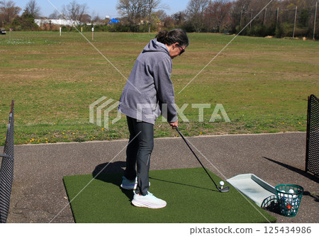 Senior Women Takes Practice Swings Take Place at a Driving Range With Open Space 125434986
