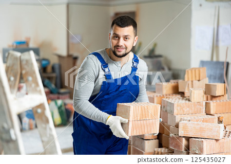 Construction worker carrying bricks at renovating object Construction worker carrying bricks at renovating object 125435027