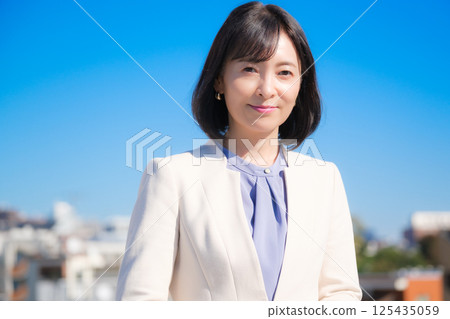 藍天下,一位自信的中年職業女性,身穿白色西裝 藍天下,一位自信的中年職業女性,身穿白色西裝 125435059