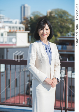 藍天下,一位自信的中年職業女性,身穿白色西裝 藍天下,一位自信的中年職業女性,身穿白色西裝 125435064