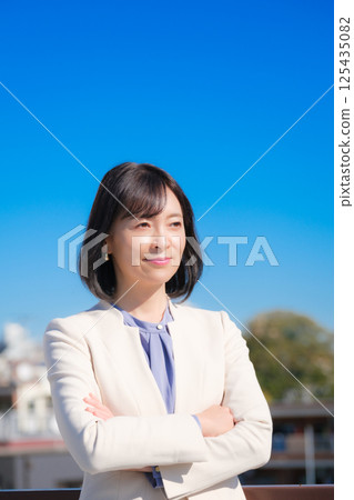 A confident middle-aged career woman in a white suit under a blue sky A confident middle-aged career woman in a white suit under a blue sky 125435082