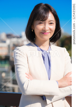 藍天下,一位自信的中年職業女性,身穿白色西裝 藍天下,一位自信的中年職業女性,身穿白色西裝 125435091