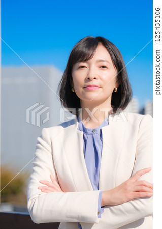 A confident middle-aged career woman in a white suit under a blue sky A confident middle-aged career woman in a white suit under a blue sky 125435106