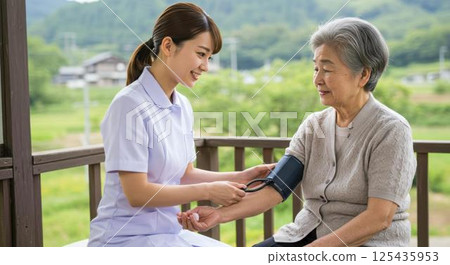 一位美麗的護士在家訪時為一位老年婦女測量血壓 一位美麗的護士在家訪時為一位老年婦女測量血壓 125435953