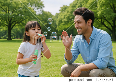 父親和女兒在公園玩肥皂泡;週末家庭時光 父親和女兒在公園玩肥皂泡;週末家庭時光 125435961