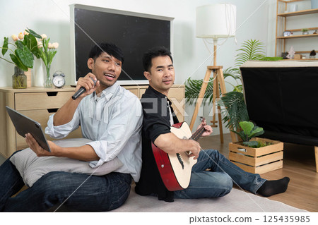 LGBT Friendship and Music. Two men enjoying a musical moment together, sharing laughter and creativity in a cozy living room. LGBT Friendship and Music. Two men enjoying a musical moment together, sharing laughter and creativity in a cozy living room. 125435985