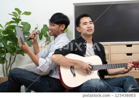Creativity and LGBT Expression. Two men engaging in a fun musical duet, showcasing their talents in a cozy environment. Creativity and LGBT Expression. Two men engaging in a fun musical duet, showcasing their talents in a cozy environment. 125436003