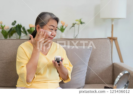 Beauty and Skincare. A senior woman applying moisturizer, showcasing her commitment to self-care. Beauty and Skincare. A senior woman applying moisturizer, showcasing her commitment to self-care. 125436012