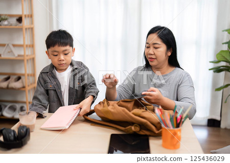 Back to School and Preparation. A mother and son organize school supplies together, preparing for the new academic year. Back to School and Preparation. A mother and son organize school supplies together, preparing for the new academic year. 125436029