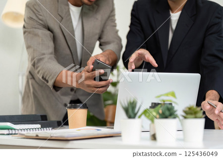 Smartphone and Collaboration. Two men discussing ideas while using a smartphone and laptop. 125436049
