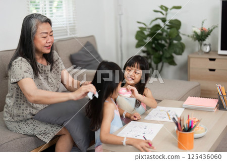 Family Time and Learning. A grandmother helps her granddaughters with their drawings and crafts. Family Time and Learning. A grandmother helps her granddaughters with their drawings and crafts. 125436060