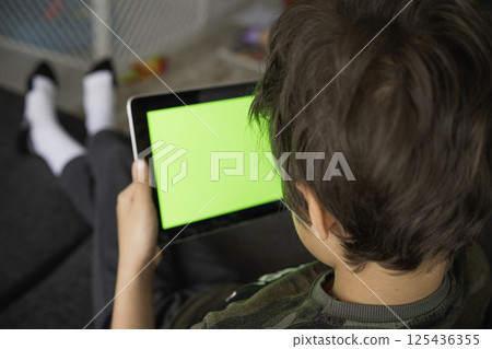 Boy using social media on tablet with chroma key background. touchscreen device for social networks browsing 125436355