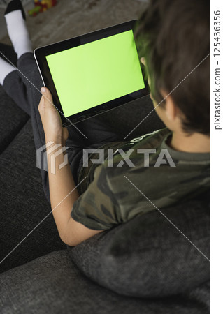 Boy using social media on tablet with chroma key background. touchscreen device for social networks browsing Boy using social media on tablet with chroma key background. touchscreen device for social networks browsing 125436356