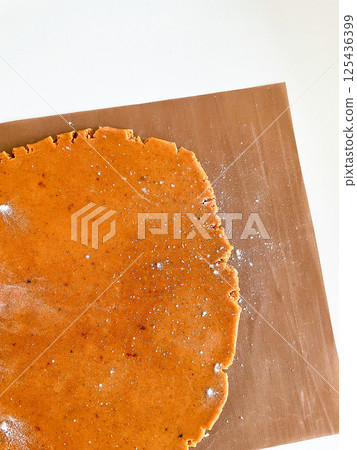 Gingerbread dough rolling on brown baking mat with flour dusting Gingerbread dough rolling on brown baking mat with flour dusting 125436399