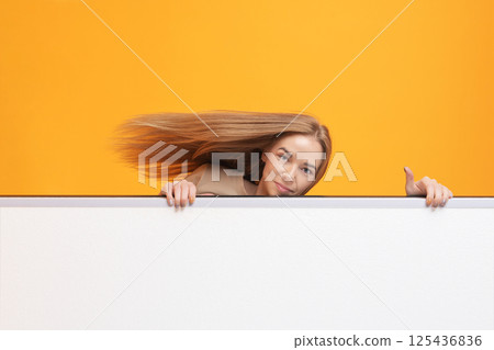 Woman Peeking Over White Panel Woman Peeking Over White Panel 125436836