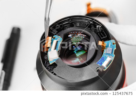 the hands of the master with gloves and a broken lens of a professional camera. 125437675