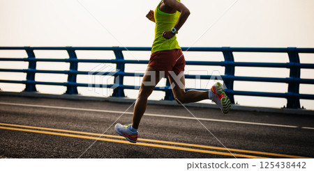 Asian fitness woman runner running on seaside bridge 125438442