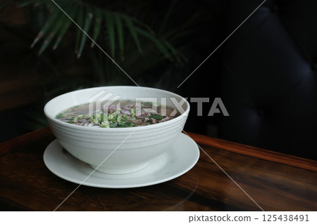 Traditional Vietnamese pho soup with beef slices served in a white ceramic bowl, copy space for text. Concept of authentic Asian cuisine, healthy food and comforting homemade meals. 125438491