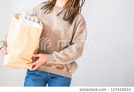 Woman Holds Paper Bag Brimming with Plastic Bottles and Packaging. Recycle and Dispose Waste Conscience Concept. 125438810
