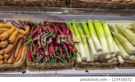Carrots chili peppers and daikon oranges and pomegranates stacked on the counter 125438872