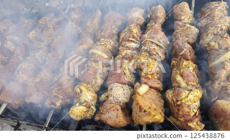 Marinated meat pieces on skewers lie on the grill and are fried on coals. 125438876