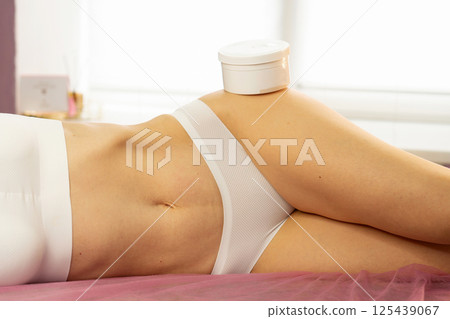 Client lies on treatment bed with container on hip 125439067