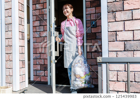 A woman taking out the trash 125439983