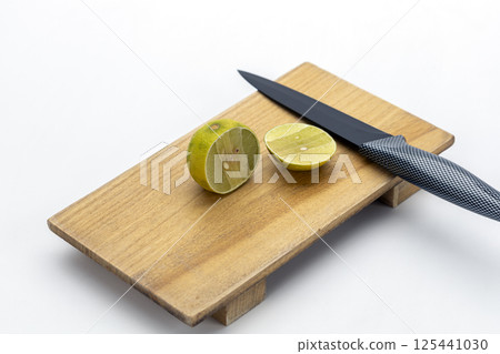 Sour flavors in Thai food: Lime wedges placed next to a black kitchen knife on a wooden cutting board. Sour flavors in Thai food: Lime wedges placed next to a black kitchen knife on a wooden cutting board. 125441030