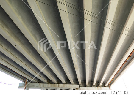 Abstract industrial photo with bottom view of a road bridge with concrete pillars. 125441031