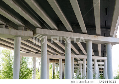 Abstract industrial photo with bottom view of a road bridge with concrete pillars. Abstract industrial photo with bottom view of a road bridge with concrete pillars. 125441033